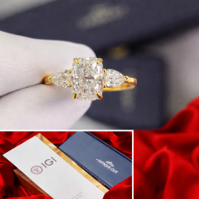 Radiant cut three-stone diamond engagement ring featuring a large rectangular center diamond with pear-shaped side diamonds in a yellow gold setting.