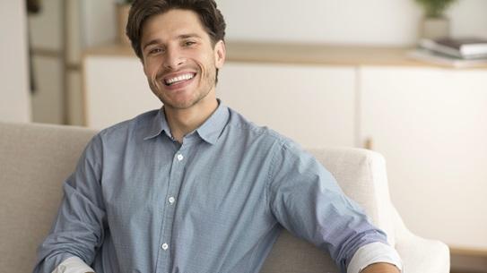 cheerful-guy-smiling-at-camera-resting-on-couch
