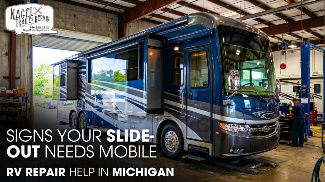An RV parked inside a workshop garage undergoing a slide-out repair job